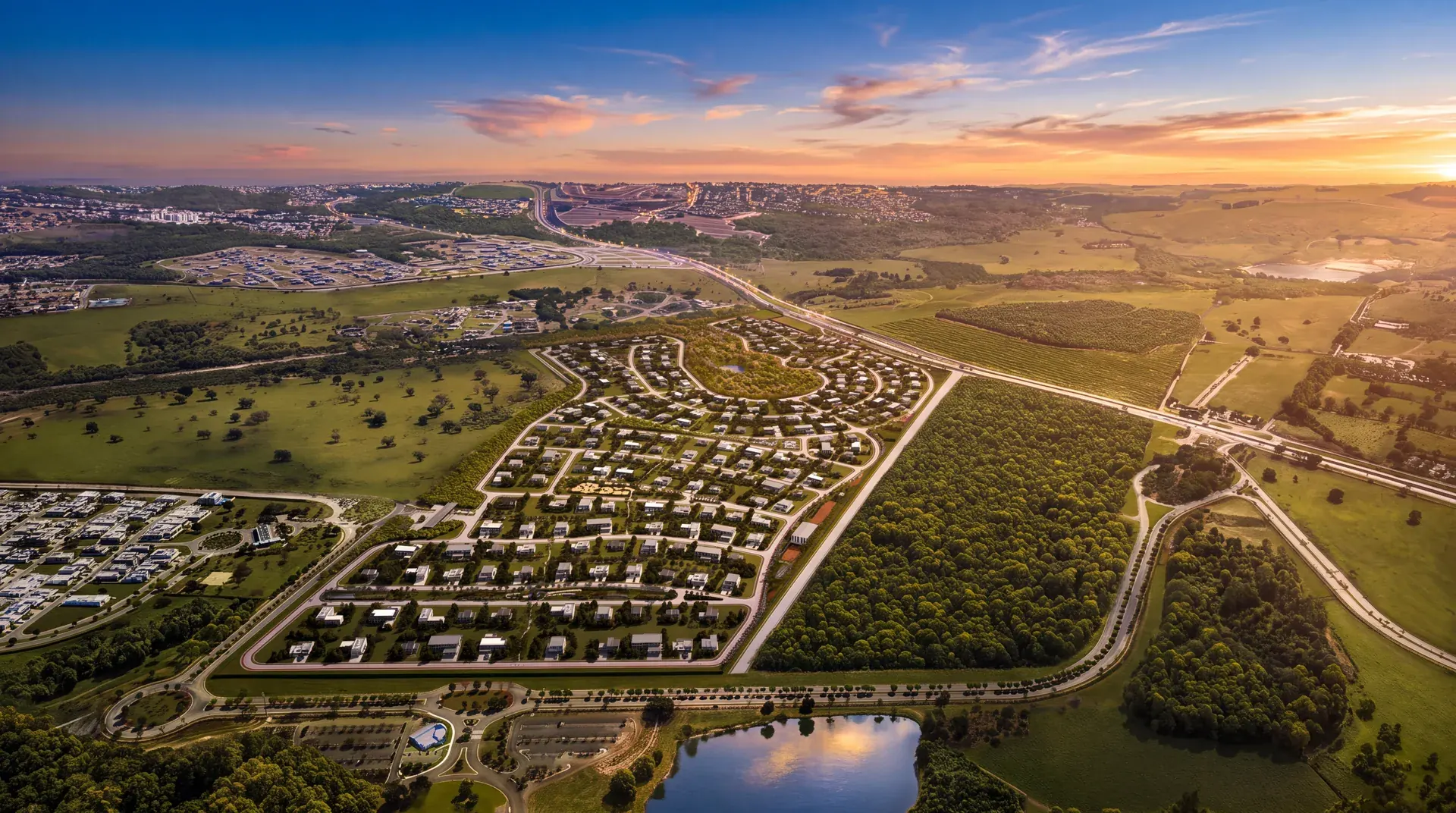 Vista aérea de um loteamento ao pôr do sol, com quadras, ruas e área verde